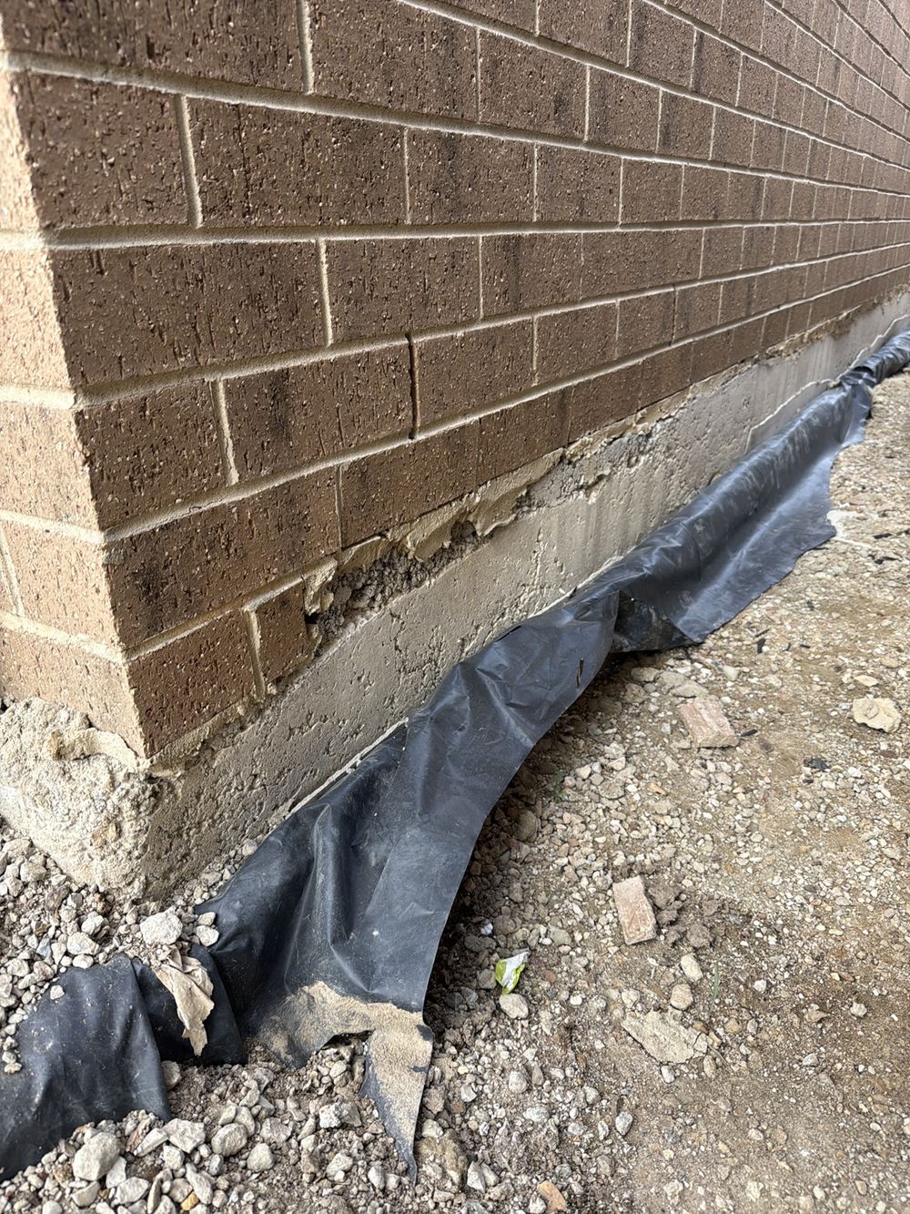 Thick mortar bed packing out an uneven slab under a garage boundary wall, Clyde North